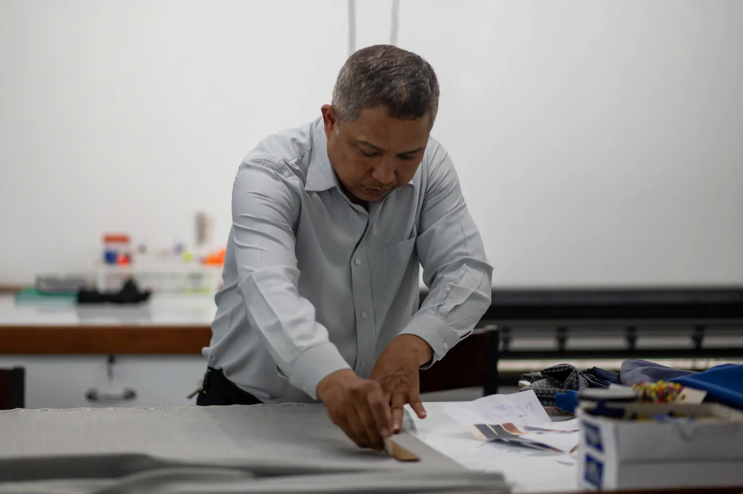 Sawasdee tailor cutting fabric by hand in the Bangkok workshop
